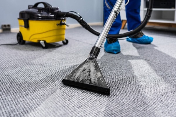Person reinigt professionell einen Teppichboden für Unternehmen